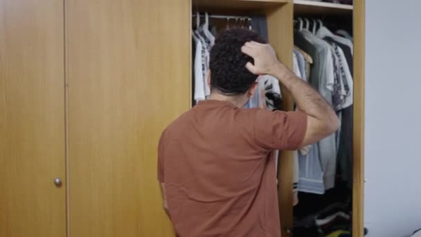 Muskulöse Lateinamerikanische Kerl Öffnet Seine Garderobe Und Schaut Auf Kleidung — Stockvideo