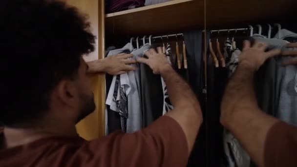 Schöner Mann Zieht Ein Bedrucktes Hemd Aus Seinem Kleiderschrank Horizontal — Stockvideo