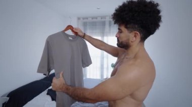 Kaslı bir adam gri bir tişörte bakıyor - 4K Yatay Video