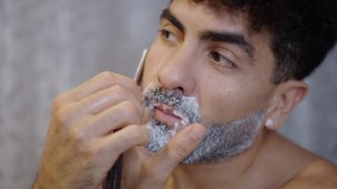 Evde jiletle tıraş olan yakışıklı bir adam - 4K Yatay video