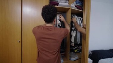 Venezuelalı çocuk dolaptan basılı bir gömlek çıkardı - 4K Yatay video
