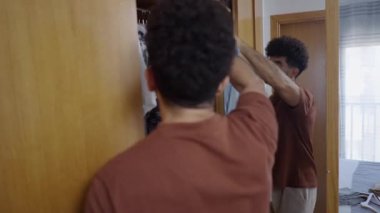 Mavi gömlek ve beyaz pantolon, Latin bir çocuk tarafından dolaptan çıkarılıyor. 4K yatay video.