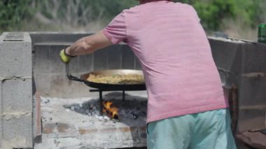 Aşçı paella 'yı ateşten çıkarır. İspanyol geleneksel yemekleri.