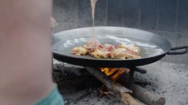 Tanınmayan aşçı tavuğu paellaya döküyor. İspanyol geleneksel yemekleri.
