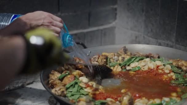 Cocinero Revuelve Paella Mientras Ayudante Vierte Agua Comida Tradicional Española — Vídeo de stock