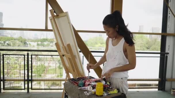 一个年轻的亚洲女孩把画笔和一个画布 4K艺术概念混合在一起 — 图库视频影像