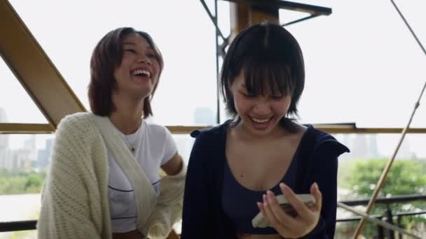 スマートフォンを見ながら2人の美しいアジアの女性が笑顔 4Kアーティスティックコンセプト — ストック動画