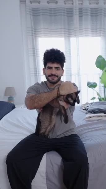 ハンサムな男は猫を抱きながら笑う Fhd垂直ビデオ — ストック動画