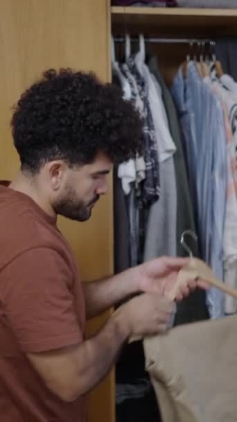Latinský Muž Otevře Skříň Vytáhne Velbloudí Kalhoty Bílou Polo Košili — Stock video