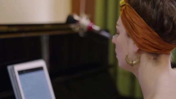 女孩在她面前的平板电脑上 靠着钢琴 4K水平录像带 热情地歌唱着 — 图库视频影像