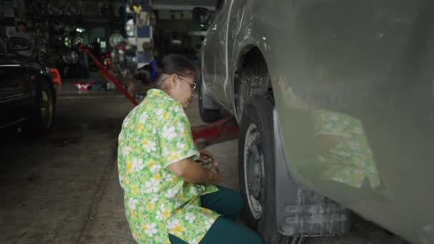 穿着花衬衫的老妇人在轮子上钉上螺栓 Horizontal Video — 图库视频影像