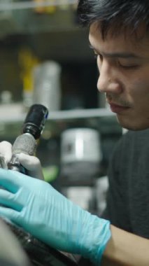 Dövme yaparken müşterinin derisini temizleyen Asyalı dövme sanatçısı - Yaratıcı konsept - FHD Dikey Video
