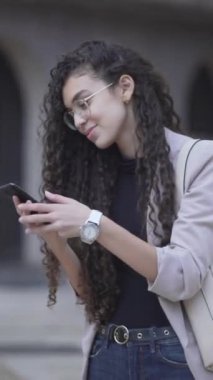 Happy Office kızı şehir parkında cep telefonu kullanıyor. Orta Çekim - Dikey