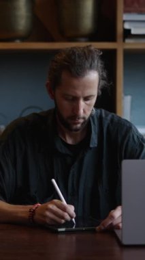 Beyaz tasarımcı bilgisayarına bakarken tabletine bir şeyler yazıyor. FHD dikey video.