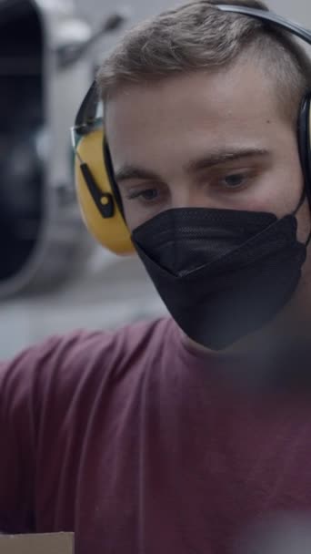 Een Jonge Werknemer Met Geluidsreductie Oor Muff Gezichtsmasker Het Vullen — Stockvideo