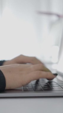 Dizüstü bilgisayarında hızla yazan genç bir kızın yakın çekim görüntüsü. Kolombiyalı bir üniversite öğrencisi evde okuyor. - 1080 dikey video