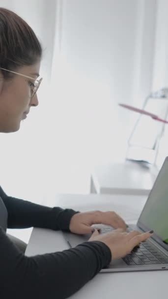 コロンビアの大学の若い学生が机に座ってノートパソコンを使っている 家で勉強する女の子 1080 垂直ビデオ — ストック動画