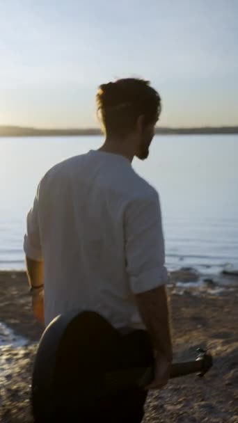 サンセット アリカンテ カントリーサイドスペインの日差しで太陽に向かってトレヴィージャピンク湖を歩いているギターを持つ若い男 ショットに続くバックビュー 垂直フルHdビデオ — ストック動画