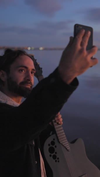 スペインのひげ付きギタリストは スペインのアリカンテのTorreviejaピンク湖で夕暮れ時に彼のギターで自分撮り写真を撮ります 垂直フルHdビデオ — ストック動画