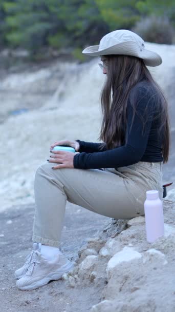 男は岩の上を歩き ハイキング旅行で食べるために女の子の隣に座る 垂直ビデオ — ストック動画
