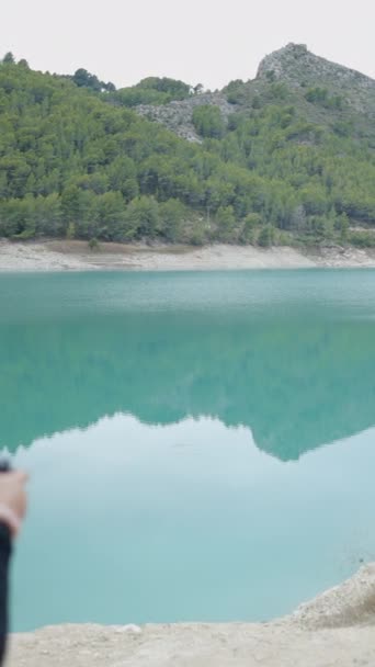 背後から見た帽子の若い女性 スペインのまだ湖の写真 垂直ビデオ — ストック動画