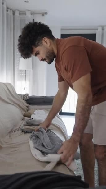スペインの自宅で服を折る現代ラテン人の男 Fhd垂直ビデオ — ストック動画