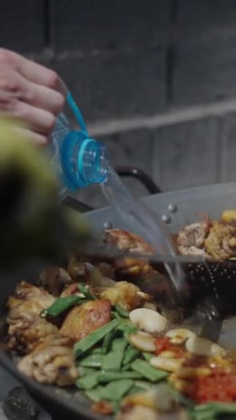Kuchař Míchá Paella Zatímco Pomocník Nalévá Vodu Španělské Tradiční Jídlo — Stock video