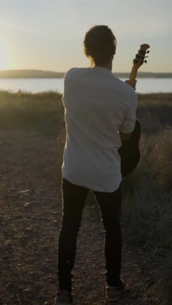 Widok Tyłu Młody Człowiek Gitarzysta Podnoszenie Ramion Górę Zachodu Słońca — Wideo stockowe
