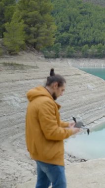 Genç adam İspanya 'daki durgun göl ve ormanın yanında İHA uçurmaya hazırlanıyor.
