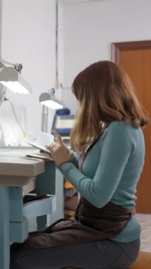 Masasındaki zanaatkar kuyumcu atölyesindeki küçük not defterine bakıyor. Orta Çekim FullHD Dikey Video