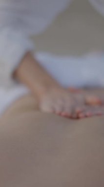 Bilinmeyen masöz sahilde masaj yapıyor. Ellere odaklan. - FullHD dikey video