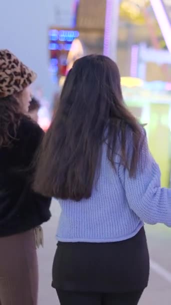 バレンシアの夜の楽しいフェアでアトラクションを探索する2人の少女 Fullhd垂直ビデオ — ストック動画