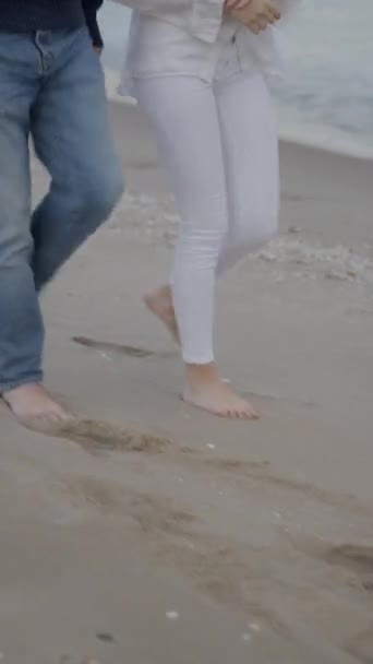 ベアフットの2人の友人の足は岸に沿って連携して歩いています 認識できない友人は散歩に行きます Fullhd垂直ビデオ — ストック動画