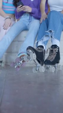 Patenli üç kız oturur ve telefona bakar ve güler, eğilir - FullHD dikey video