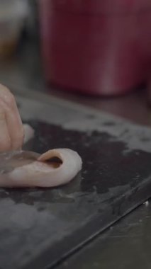 Erkek şef kesme tahtasında keskin bıçakla çiğ beyaz balığı dilimler - FullHD dikey video