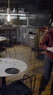 Kısa saçlı kadın boş restoranda tabak ve bardakları taşıyor - FullHD dikey video