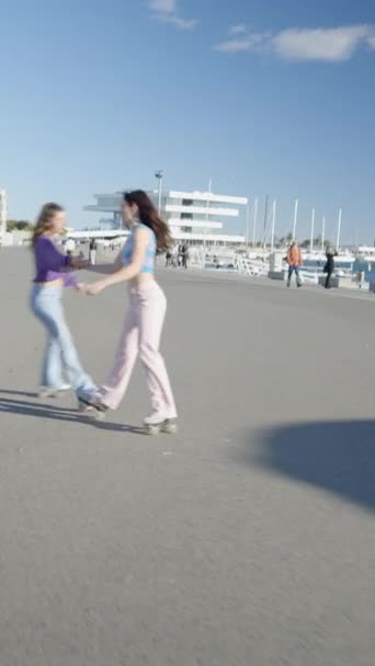 两个女孩手牵着手 在阳光下旋转或滚动溜冰鞋 Fullhd垂直视频 — 图库视频影像