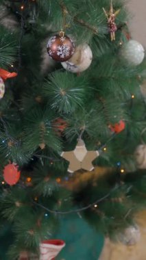 Kadın Noel ağacına asılmak için bir kutu ışıltılı Noel süsü getiriyor. raf odağı - Dikey FullHD video