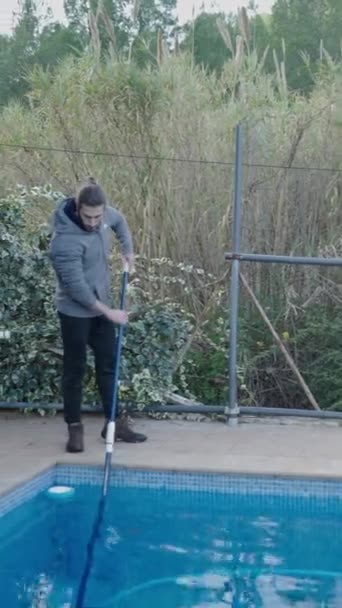 田舎の家でプールを掃除する若者 ハウスキーピングコンセプト フルHd垂直ビデオ — ストック動画