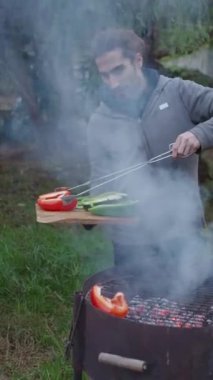 Genç İspanyol adam ormandaki bahçe evinde sebze pişiriyor - FullHD dikey video