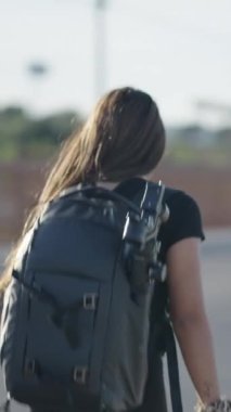 Sırt çantalı genç bir kadın yol kenarında yürüyor - FullHD dikey video