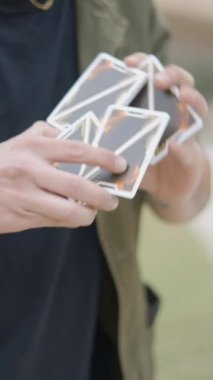 Sihirbaz iskambil kâğıdıyla numara yapıyor. Profesyonel sokak sihirbazı etkileyici bir el kartı hilesi sergiliyor. - FullHD dikey video