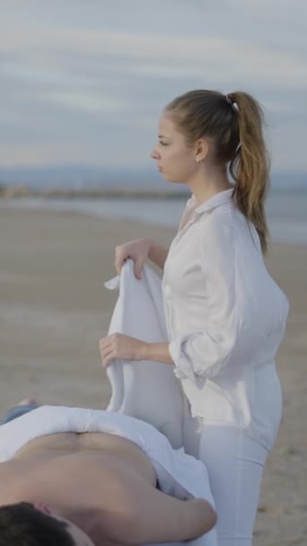 Іспанський Масажист Тримає Рушник Щоб Покрити Клієнта Масажі Пляжі Вітер — стокове відео