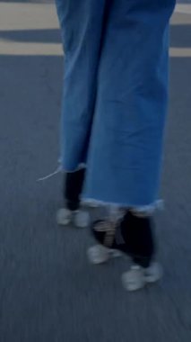 Mavi kotlu kız güneşli limanda paten kayıyor, yerden yukarı doğru eğiliyor - FullHD dikey video