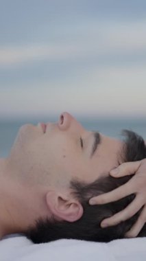 Genç İspanyol erkek baş masajı yaptırırken rahatlıyor, masözün manzarası aşağıya bakıyor - FullHD dikey video
