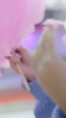 Kadınların elleri bir lunaparkta yumuşak pembe pamuklu pamuklu diş ipine dokunuyor - yakın plan FullHD dikey video