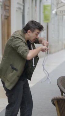 Sokak sihirbazı kafeterya masasında oturan kişiye ip sihirbazlığı yapıyor. - FullHD dikey video