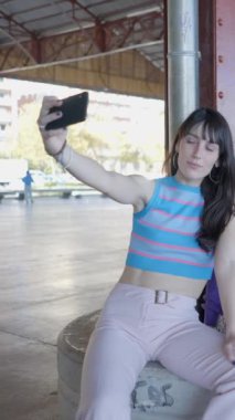 Üç mutlu kız açık havada paten kayıyor ve telefonla selfie çekiyor.