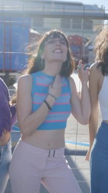 Rüzgarlı bir günde metal çitin yanında lolipopları olan üç siyah saçlı kız - FullHD dikey video