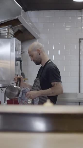 男性シェフはレストランキッチンで働いています 前景でぼやけたオブジェクト Fullhd垂直ビデオ — ストック動画